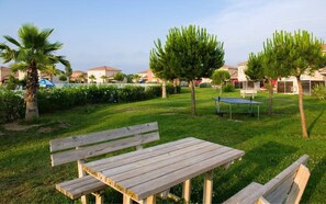 A grassy outdoor area with a wooden bench, a table, and a tennis table. - Fabregues Villa With Shared Pool (Fabregues)