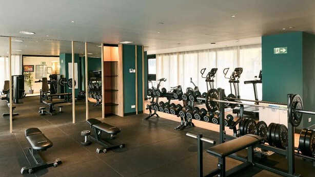 Ett gym med utrustning för styrketräning, träningsbänkar och löpband.