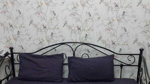A black metal sofa with two cushions against a floral wallpaper background. - The Shepherd Bush Stay in London by Gndj (London)
