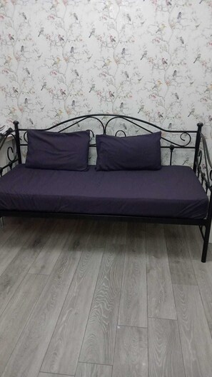 A black metal sofa with two cushions against a floral wallpaper background. - The Shepherd Bush Stay in London by Gndj (London)