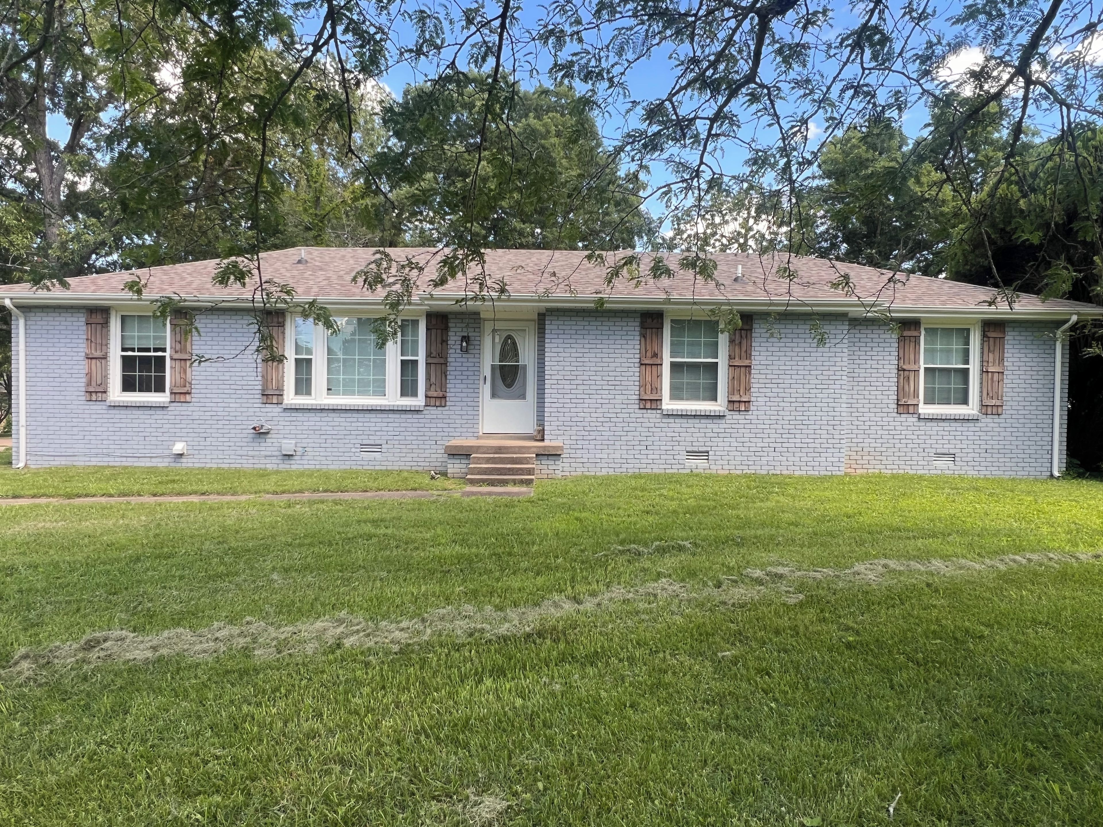 A single-story house with a front porch, a brick facade, and a small front yard.