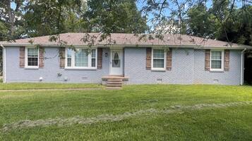 A single-story house with a front porch, a brick facade, and a small front yard.