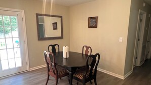 Un comedor con una mesa redonda, cuatro sillas, un espejo y dos cuadros en la pared.