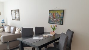 Ein Essbereich mit Tisch, Stühlen, einer Couch und zwei Wandbildern.