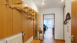 Ein Flur mit Holzvertäfelung, einem Heizkörper, einer Bank und einer Tür mit Kleiderhaken.