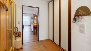 Ein Flur mit Holzboden, einer Tür im traditionellen japanischen Stil und einer wandmontierten Leuchte.