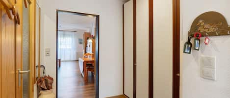 A hallway with a wooden floor, a door with a traditional Japanese design, and a wall-mounted light fixture.