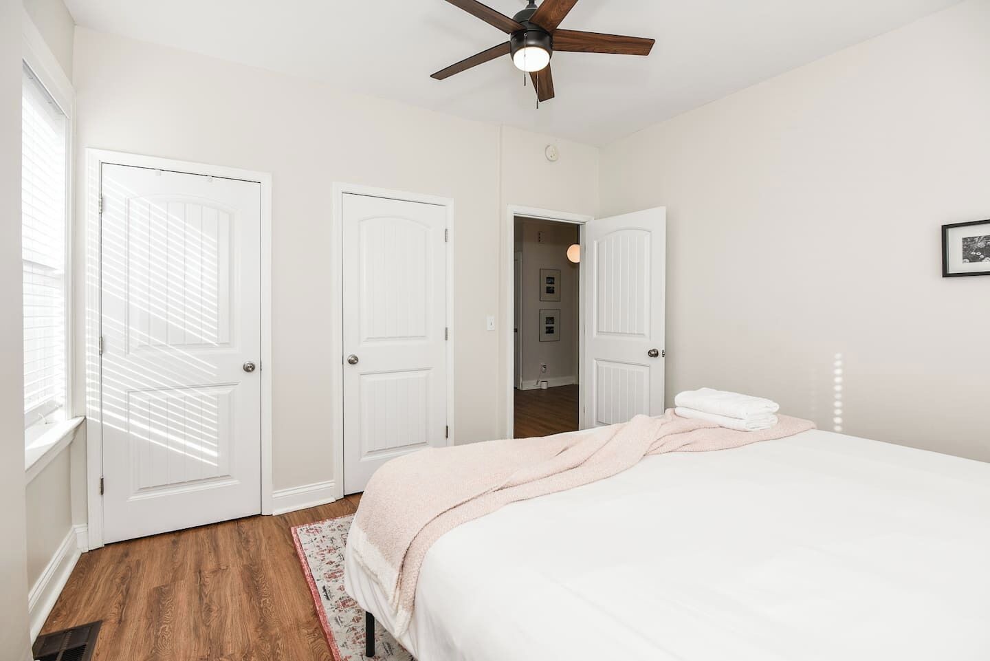 A bedroom with a bed, a ceiling fan, and white doors.