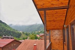 Ein hölzerner Balkon mit Blick auf ein dörfliches Bergpanorama.
