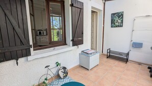 Une terrasse avec un vélo, une petite table et un meuble blanc.