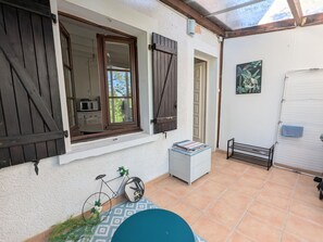 Eine Terrasse mit einem Fahrrad, einem kleinen Tisch und einem weißen Schrank.