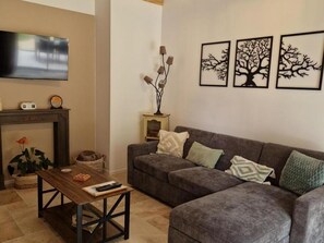 A living room with a grey sofa, a wooden coffee table, a fireplace, and wall-mounted artwork.