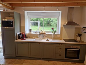 Eine moderne Küche mit Backofen, Mikrowelle und einem Fenster mit Blick auf Grünflächen.