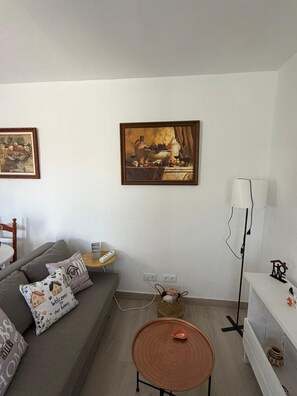 A living room with a grey sofa, a small round table, a lamp, and two framed artworks on the wall. - A&N Playa Madrid 1, Almayate (Vélez Málaga)