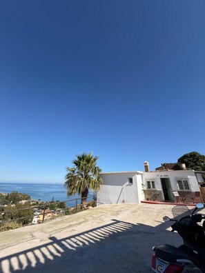 A coastal property with a white building, a palm tree, and a Yamaha scooter. - A&N Playa Madrid 1, Almayate (Vélez Málaga)