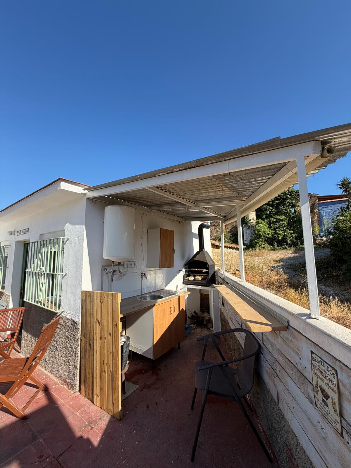 An outdoor kitchen area with a grill, a sink, and a wooden bench.