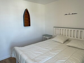 A bedroom with a bed, a nightstand, a wooden shelf, and a wall decoration. - Modern apartment, pets allowed - 4 guests (Dives-sur-Mer)