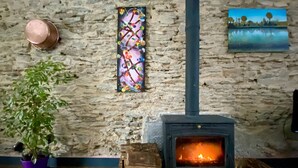 Ein rustikaler Raum mit Steinwand, Holzboden, Kamin, Blumentopf und Kunstwerken.