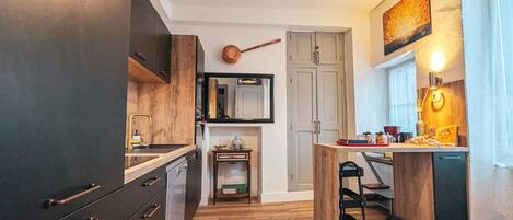 A modern kitchen with dark cabinetry, a wooden island, and a hanging pendant light.