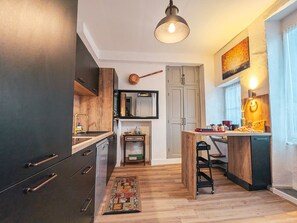 A modern kitchen with dark cabinetry, a wooden island, and a hanging pendant light.