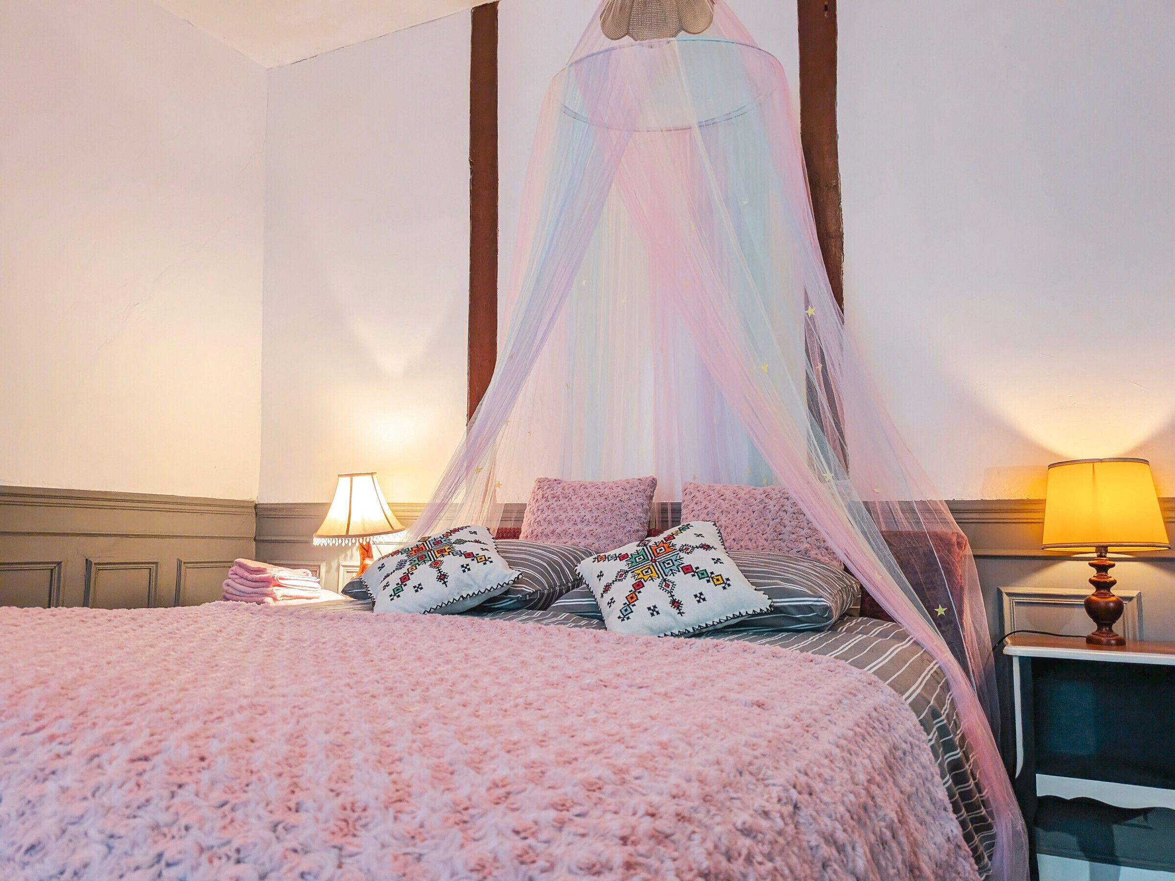 A bed with a canopy, pillows, and bedside lamps.