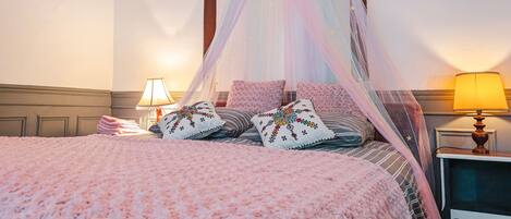 A bed with a canopy, pillows, and bedside lamps.