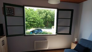 Ein Zimmer mit Fenster, einer Couch, einem Tisch und einer Heizung.