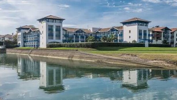 A waterfront hotel with multiple buildings, a canal in front, and a clear sky. - Charming studio - 4 guests, 2 mins to beach (Urrugne)