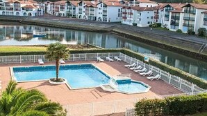 A hotel with a swimming pool, a palm tree, and a view of a river. - Charming studio - 4 guests, 2 mins to beach (Urrugne)