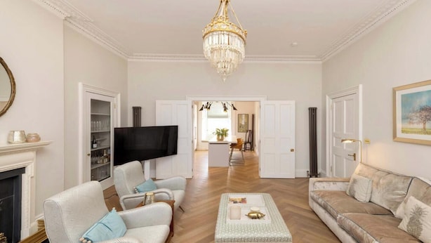 A spacious living room with a chandelier, a fireplace, and a television. - Saxecoburg Residence Place (Edinburgh)