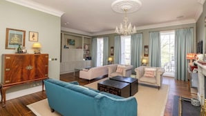 A spacious living room with a blue sofa, a fireplace, and a chandelier. - Saxecoburg Residence Place (Edinburgh)