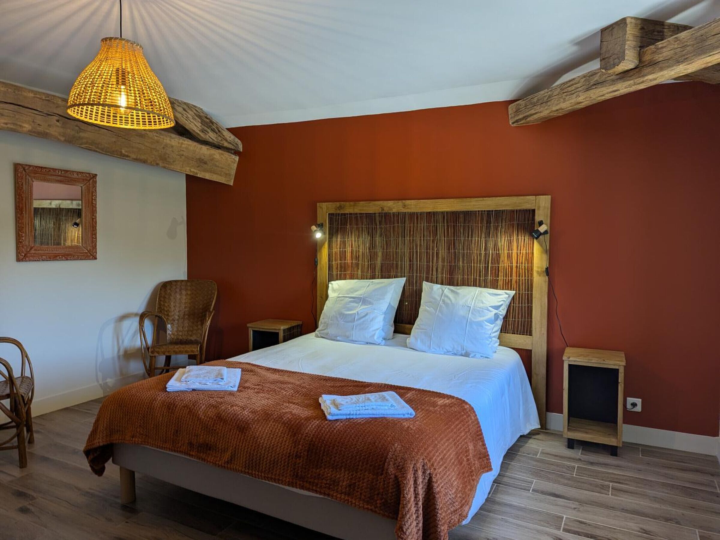 Una cama con una manta marrón, un cabecero de madera y una lámpara colgante.