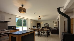 A modern kitchen with a central island, a dining area with a table and chairs, a built-in stove, and a large window. - House with private pool, pets - 8 guests (RONSENAC)