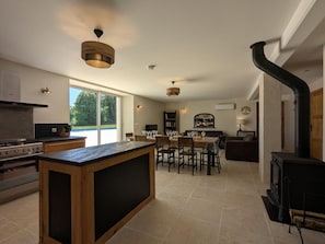 A modern kitchen with a central island, a dining area with a table and chairs, a built-in stove, and a large window. - House with private pool, pets - 8 guests (RONSENAC)