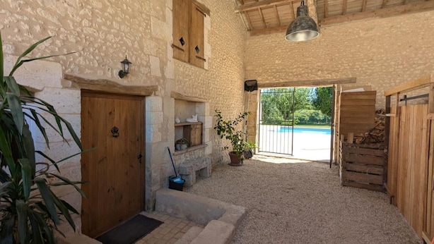 A rustic stone building with a wooden door, a small window, and a doorbell. There is a potted plant, a metal bucket, and a wooden bench. - House with private pool, pets - 8 guests (RONSENAC)