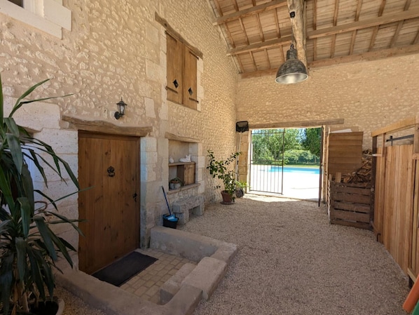 A rustic stone building with a wooden door, a small window, and a doorbell. There is a potted plant, a metal bucket, and a wooden bench. - House with private pool, pets - 8 guests (RONSENAC)