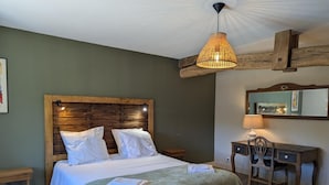 A bedroom with a wooden headboard, a bed with white bedding, a green throw blanket, a desk with a chair, and a hanging light fixture. - House with private pool, pets - 8 guests (RONSENAC)
