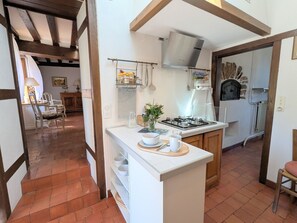 Une cuisine équipée d’une cuisinière à gaz, de meubles blancs et d’un porte-ustensiles suspendu.