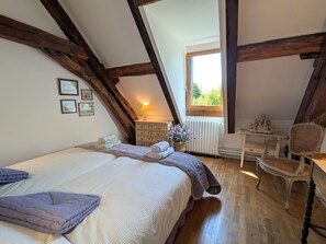 Une chambre à coucher comprenant un lit, une commode, une chaise et une fenêtre donnant sur un paysage agréable.