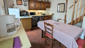 Cozinha com armários de madeira, micro-ondas, fogão e mesa com toalha de mesa estampada.