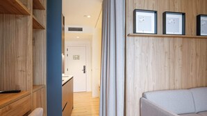 Una habitación de hotel moderna con un armario de madera, un escritorio, un sofá y cuadros en la pared.