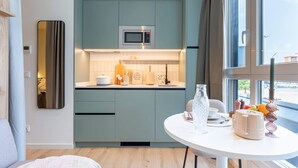 Una cocina moderna con microondas integrado, un ventanal grande y una zona de comedor con una mesa lista para dos personas.