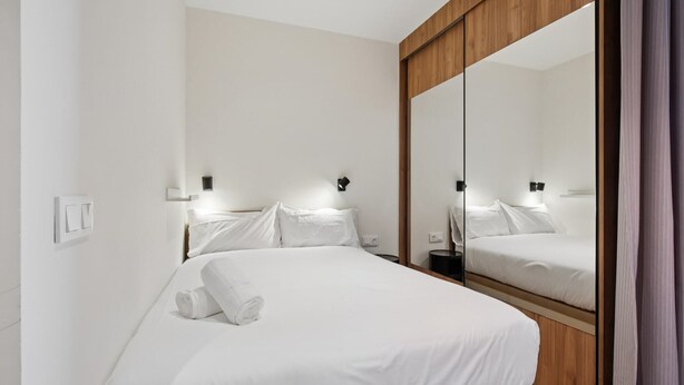 Una habitación de hotel con una cama grande, un armario de madera y un espejo.