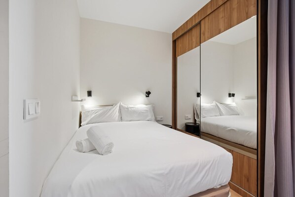 A hotel room with a large bed, a wooden wardrobe, and a mirror.