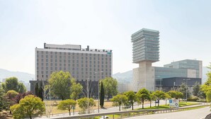 Un edificio moderno con techo plano y un amplio estacionamiento al frente.