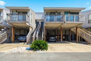 A two-story building with balconies, a central staircase, and parked cars. - Welcome to Ocean Mile K-3! (St. George Island)