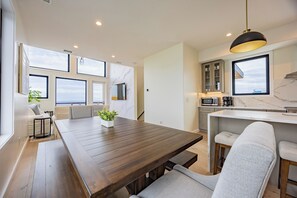 Een moderne keuken met een marmeren aanrechtblad, een eethoek met een houten tafel en een groot raam met uitzicht.
