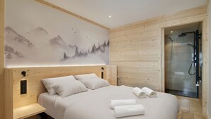 Un dormitorio con una cama grande, una banca, ducha y un mural en la pared.