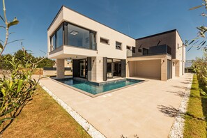 A modern two-story house with a swimming pool, large windows, and a garage. - Villa Weiss 1 (Vir)