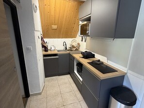Una cucina compatta con mobili grigi, un piano di lavoro in legno, un lavandino e una lavastoviglie.